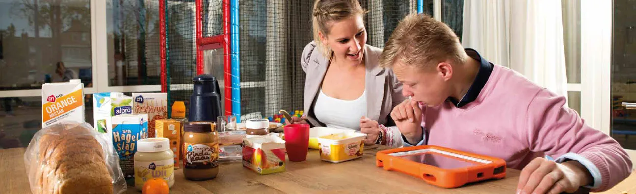 A user and a carer working with the app at the kitchen table